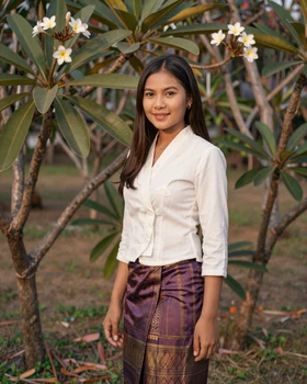 Beautiful Laotian woman in traditional purple sinh skirt standing in a tropical garden in Laos