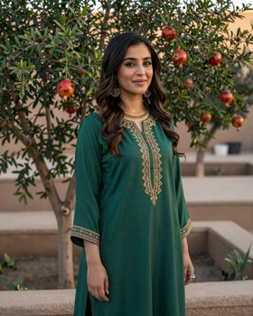Beautiful Afghan woman in traditional emerald green embroidered dress in garden setting
