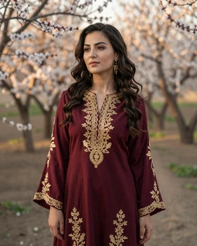 Beautiful Tajik woman wearing traditional atlas silk dress in apricot garden in Dushanbe